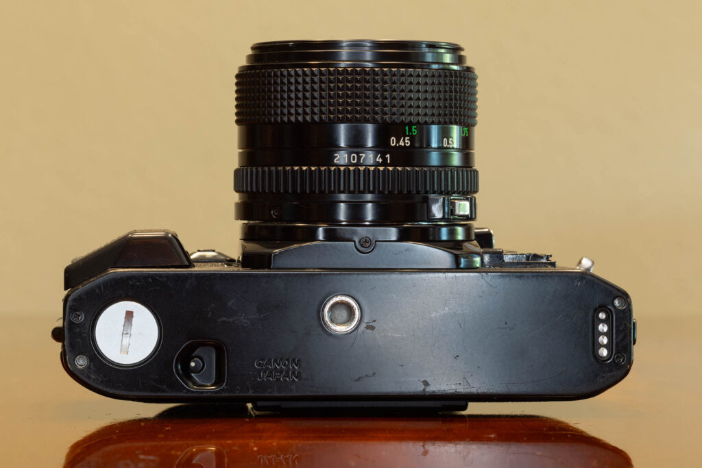 Bottom of Canon A-1 SLR film camera from the late 1970s, made in Japan. Lens is a Canon FD 50mm f1.4.