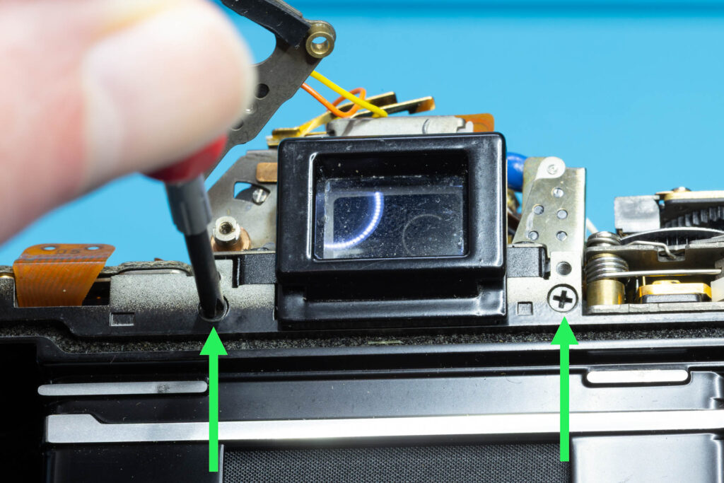 Canon A-1: Removal of mirror box - Remove two screws near the eyepiece