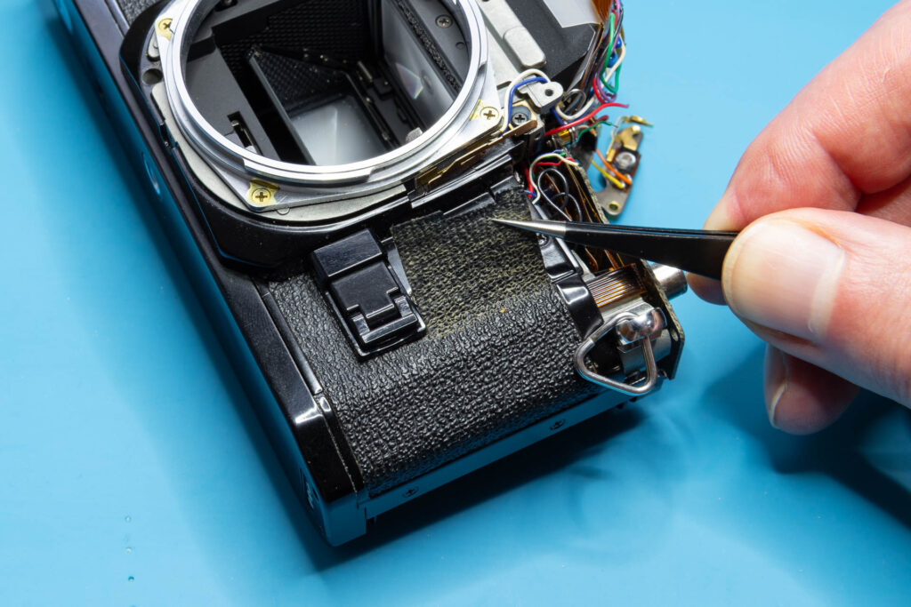 Canon A-1: Removal of mirror box - Grab the edge of the right-side leatherette and start pulling
