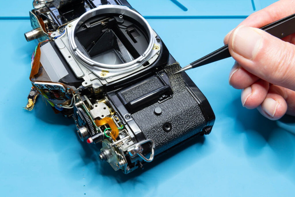 Canon A-1: Removal of mirror box - Grab the edge of the left-side leatherette and start pulling
