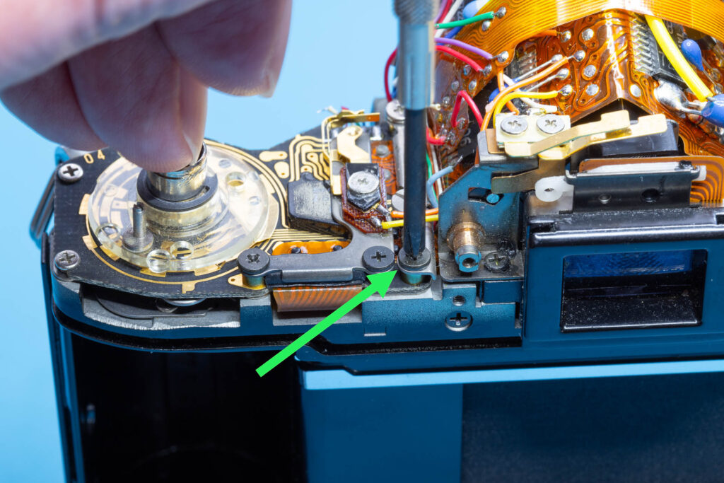 Canon A-1: Removal of mirror box - Remove the cross-head screw of the SAVE connector plate