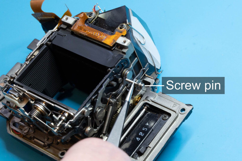 Canon A-1: Screw pin of mirror-return spring removed from mirror-control unit