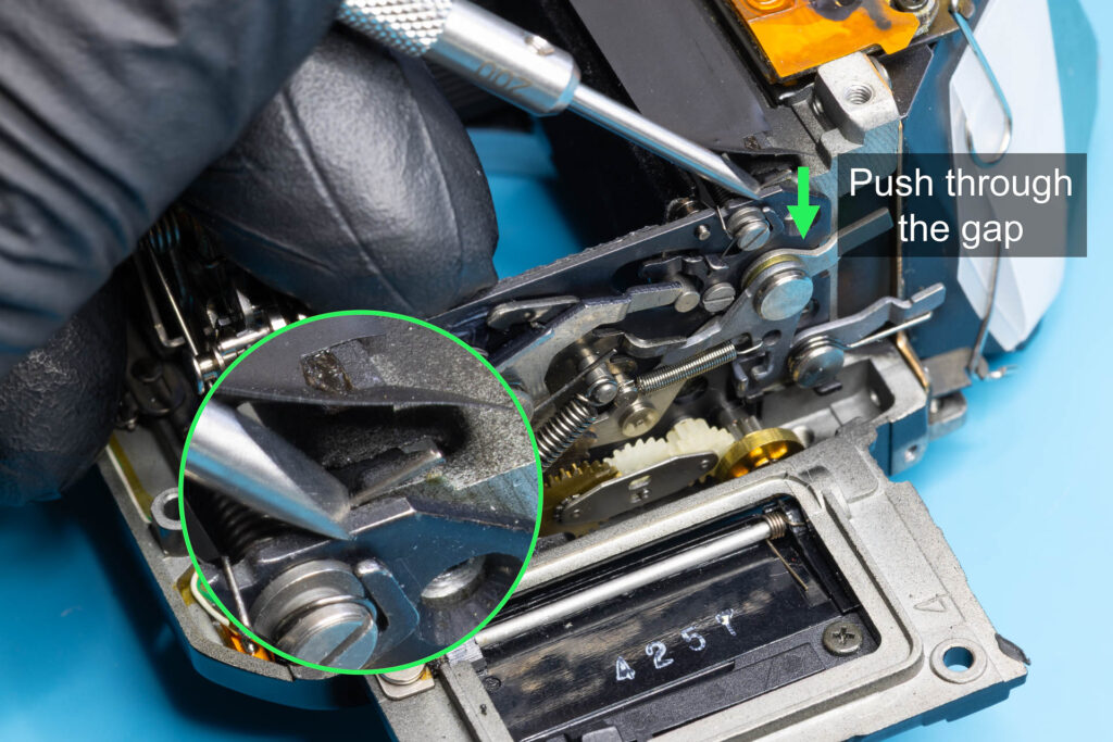 Canon A-1: Push the short leg of the mirror-return spring through the gap